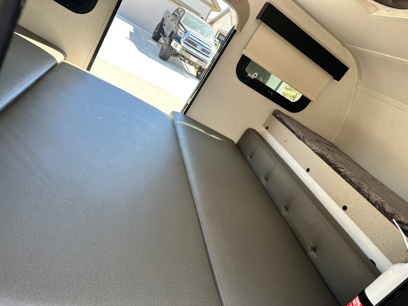 Inside a cozy **RV rental**: convertible seating/beds, bunk bed, and a truck visible outside. Ready for your next adventure.