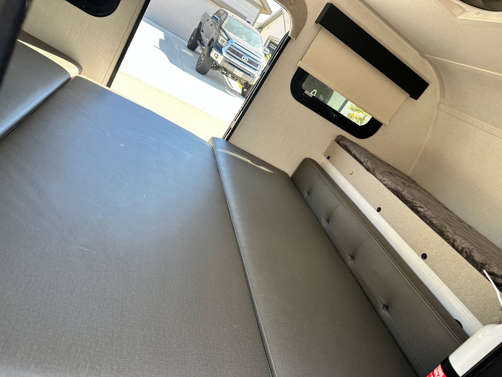 Inside a cozy **RV rental**: convertible seating/beds, bunk bed, and a truck visible outside. Ready for your next adventure.