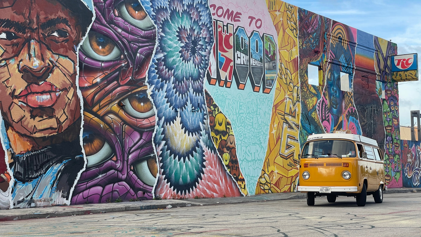 Dynamic street art mural and a vintage yellow VW Westfalia, an ideal RV rental for exploring vibrant urban landscapes.