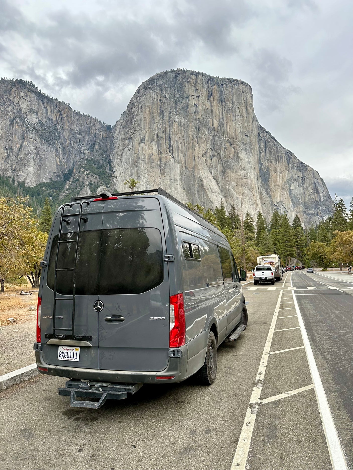 Grey Sprinter rv rental van parked roadside, facing towering El Capitan in Yosemite. Great mountain views.