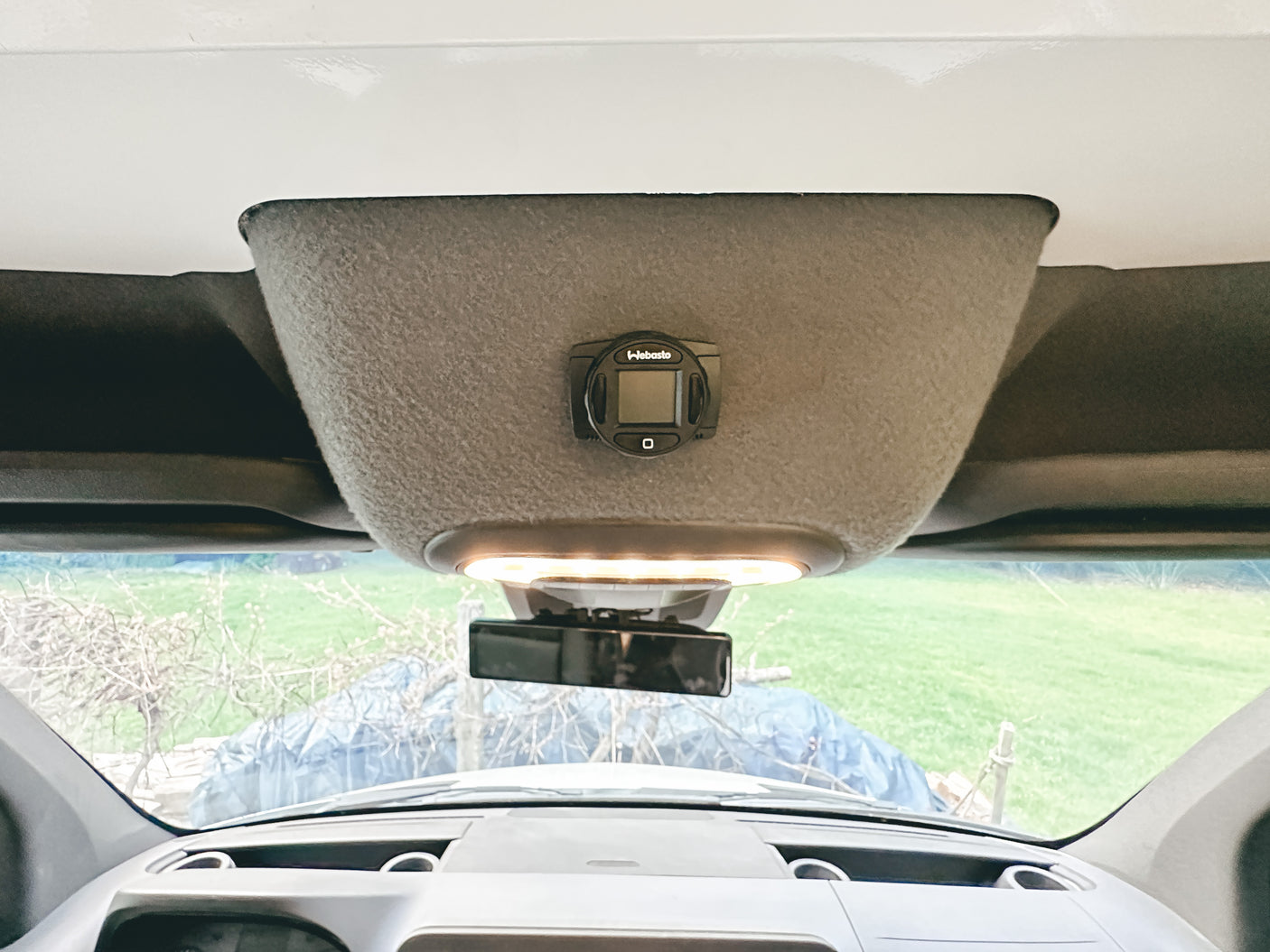 Inside an RV rental: a Webasto heater control panel, dashcam, and overhead light on a custom console.