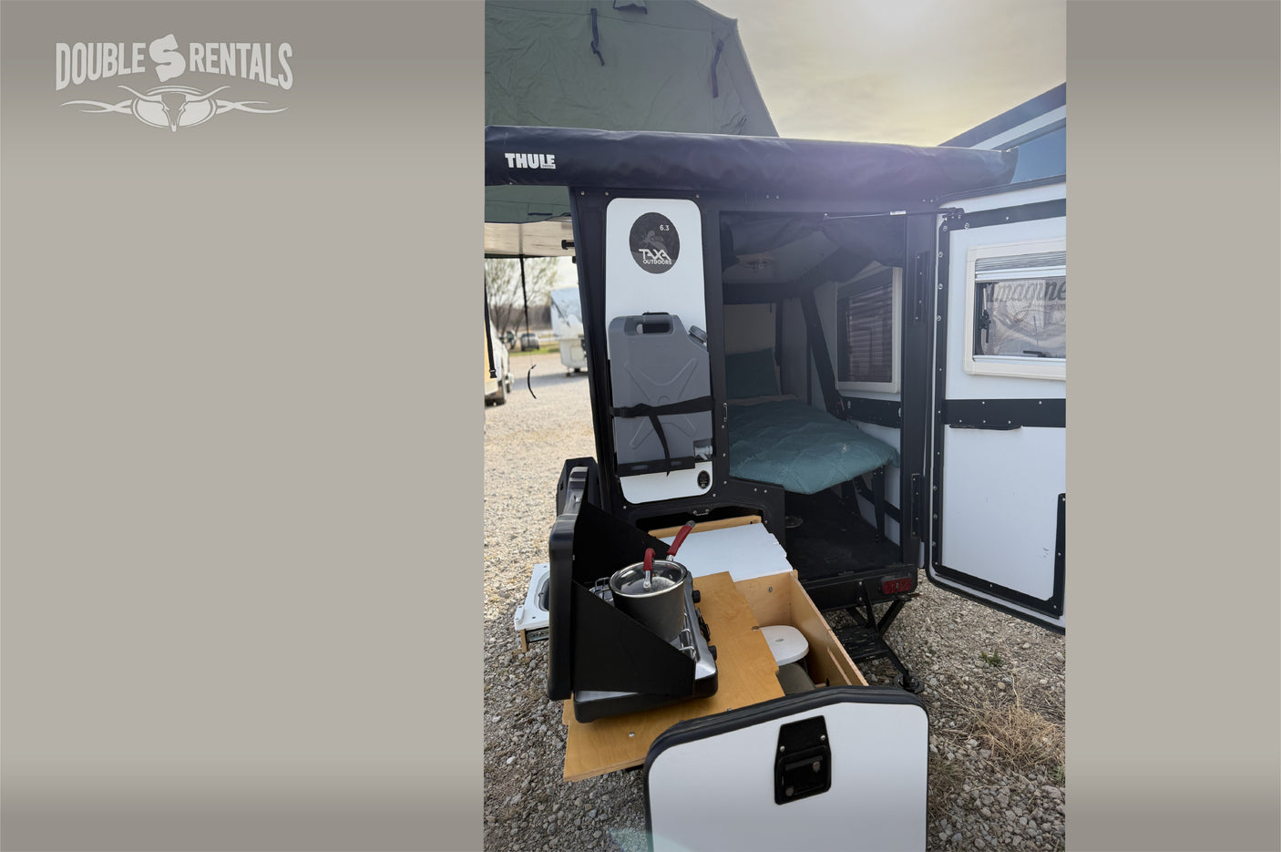 RV rental: TAXA Outdoors camping trailer with open side showing bed, outdoor kitchen & Thule awning.