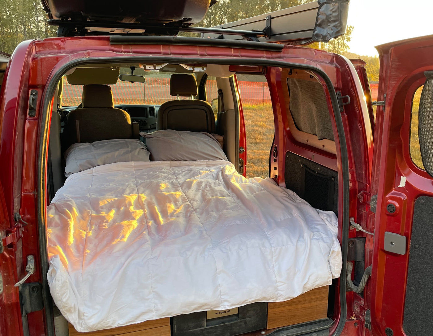 Sleep comfortably in this red **rv rental**. Inside, a cozy bed with white linens awaits your **van life** trip. — photo 8