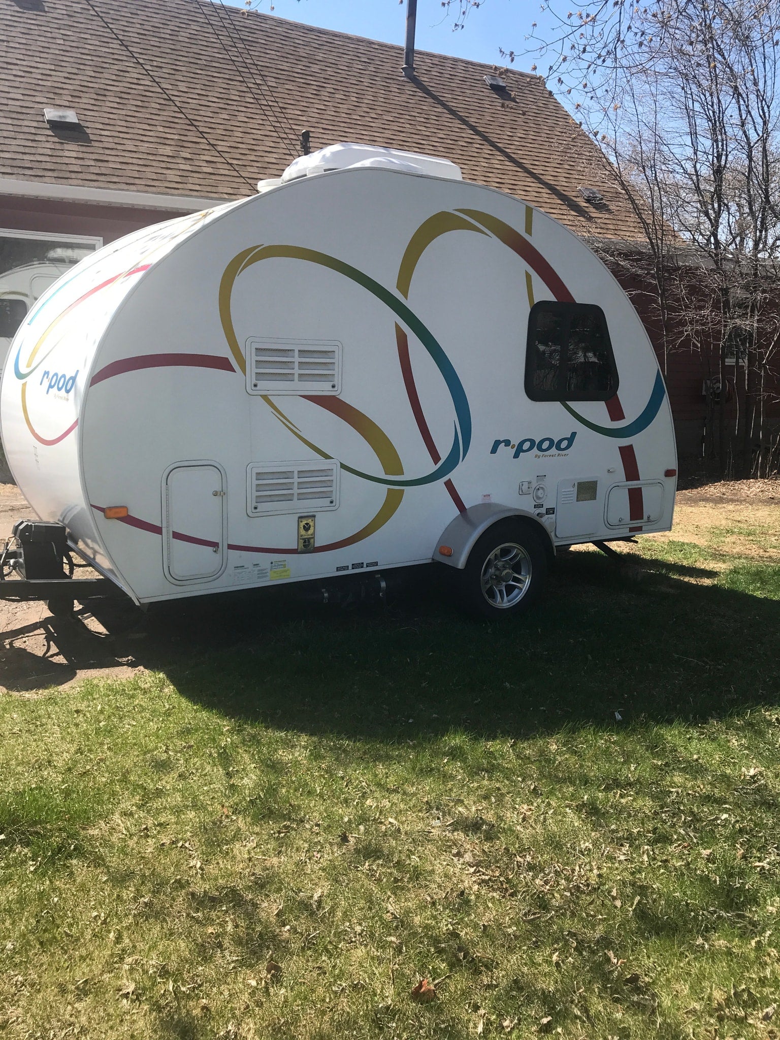 parked outdoors on gravel. Perfect for camping adventures.|A compact white r-pod travel trailer