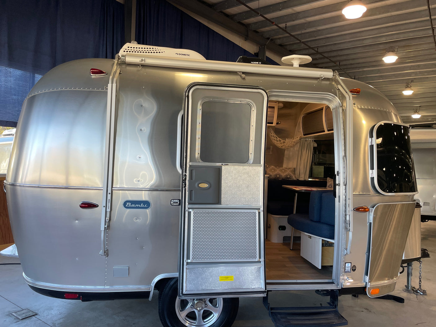 A silver Airstream Bambi travel trailer with an open door, revealing its cozy interior. Great for your next rv rental.