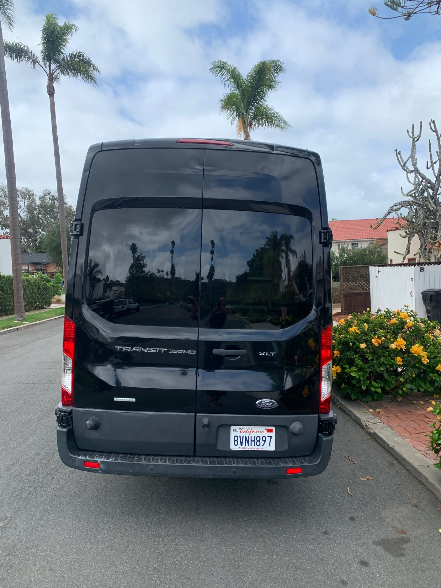 Rear view of a black Ford Transit 350HD XLT van, popular for rv rental conversions, parked on a California street.
