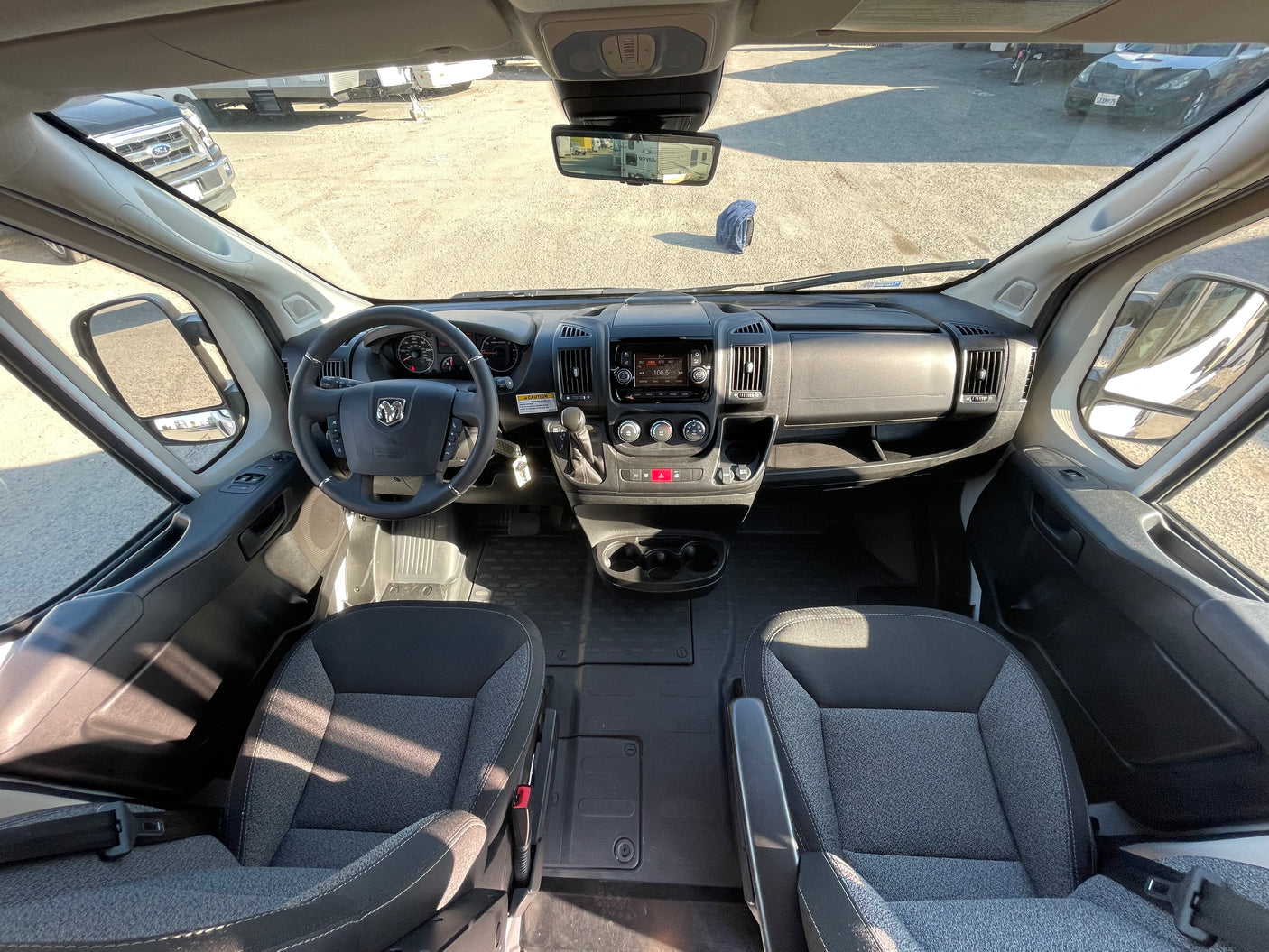 RV rental: Bright, wide-angle view of a camper van's cockpit, showing steering wheel, dashboard, and front seats.