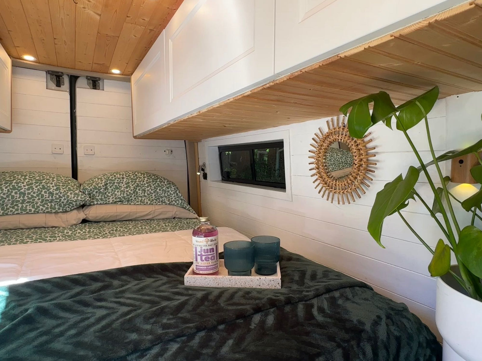 showing a kitchen setup in the foreground.|Modern RV rental interior with a cozy bed