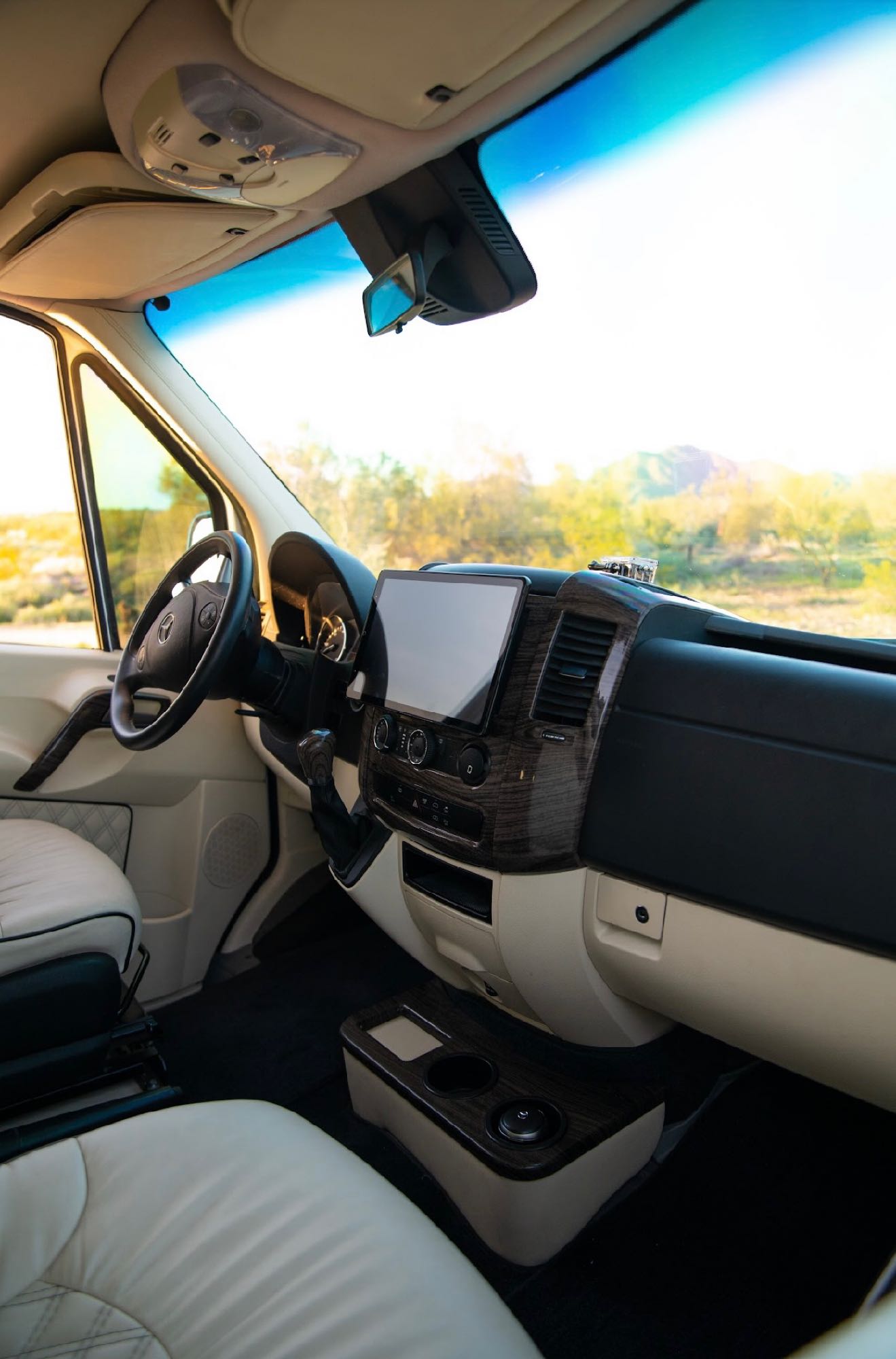 Interior of a modern Mercedes-Benz RV rental. Cream leather seats, wood trim dashboard, and large infotainment screen shown.