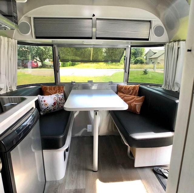 RV rental interior shows a bright Airstream dinette with black benches, a white table, and large windows looking out.