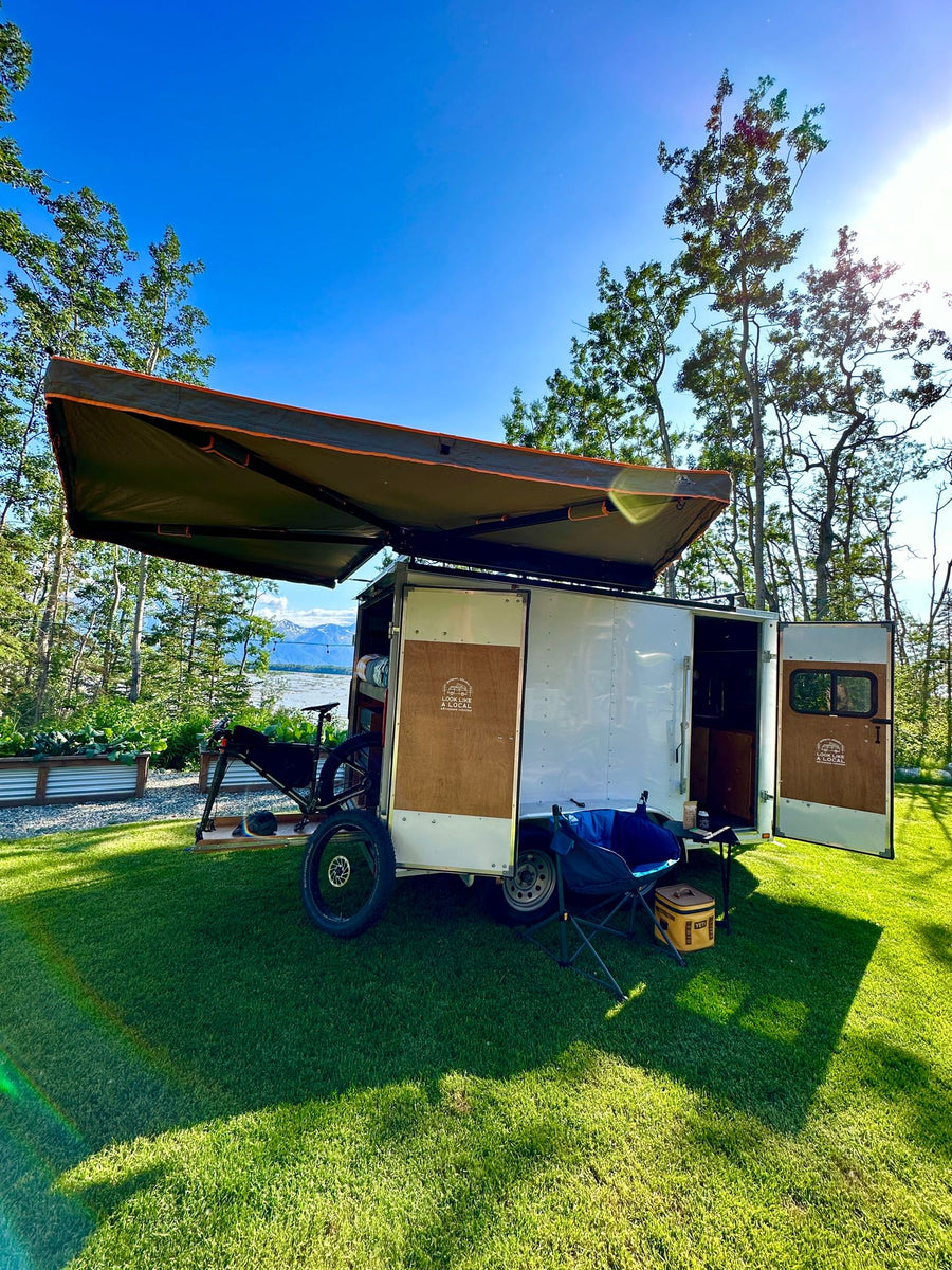 and spare tire.|RV rental interior: cozy wood-paneled camper van with a raised bed