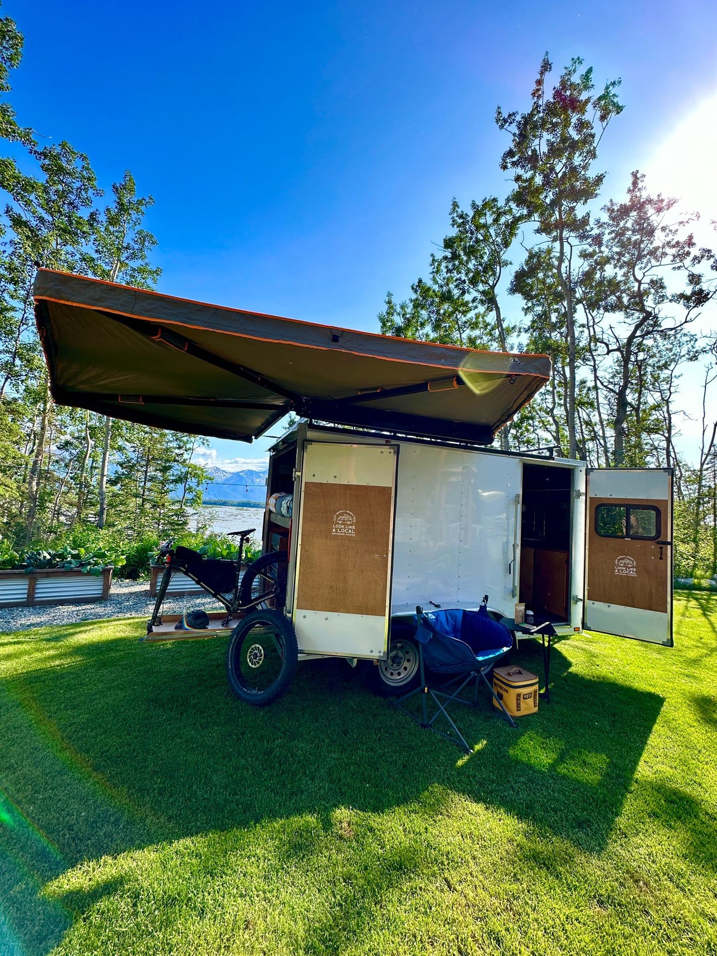 and spare tire.|RV rental interior: cozy wood-paneled camper van with a raised bed