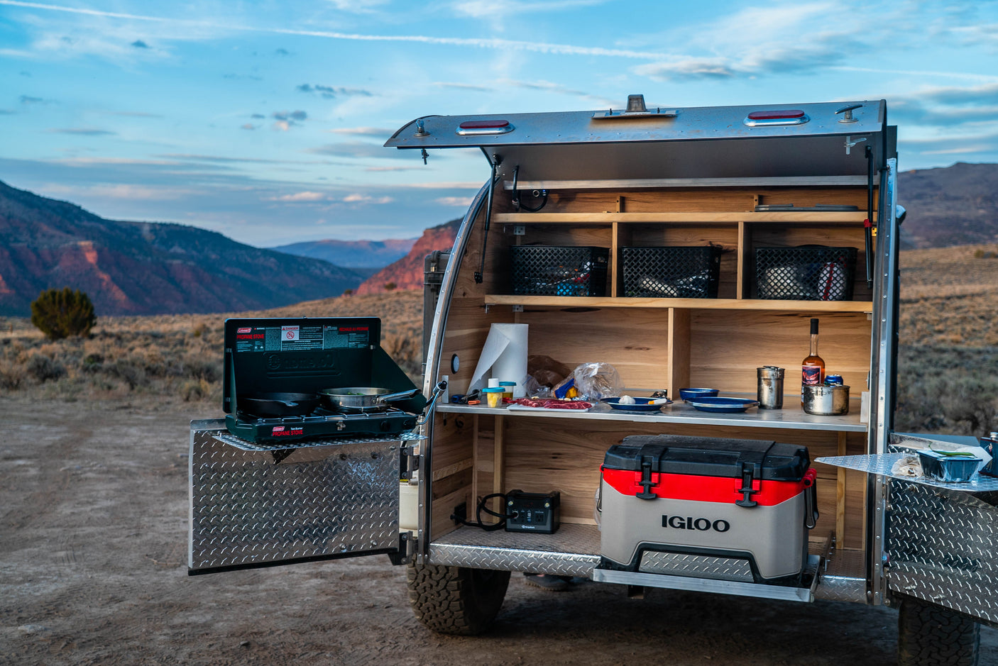 This rv rental teardrop camper offers an outdoor kitchen with stove, cooler, and shelving, perfect for scenic camping trips.