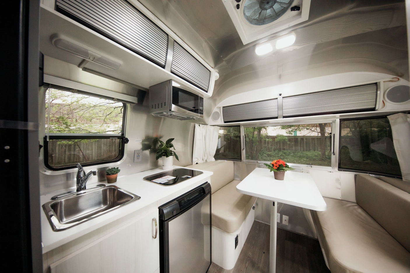 Explore a sleek RV rental kitchen and dining area, featuring a sink, microwave, fridge, and comfortable dinette.