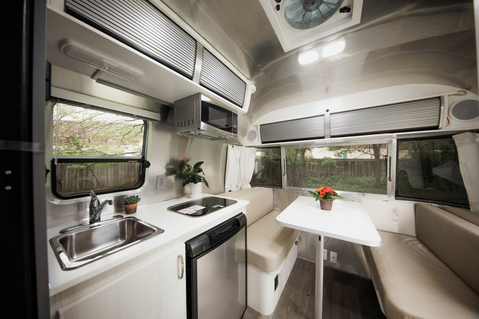 Explore a sleek RV rental kitchen and dining area, featuring a sink, microwave, fridge, and comfortable dinette.