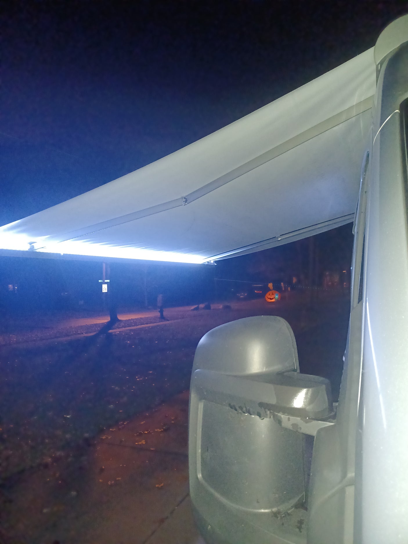 Night view from an RV rental: a bright LED-lit awning and side mirror. Great for evening camping.