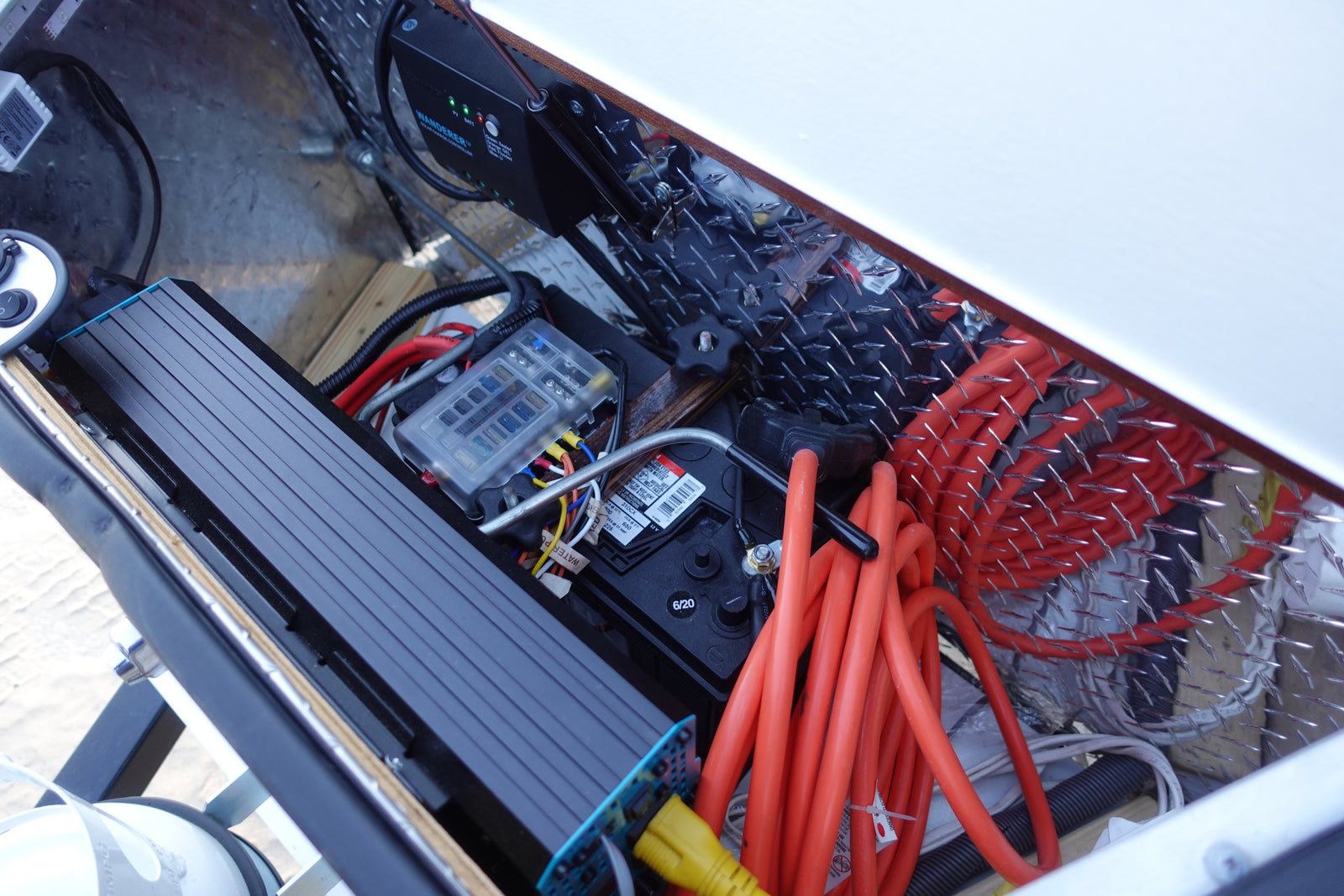 RV rental's electrical system showing battery, Wanderer solar charge controller, inverter, and fuse box with wiring.