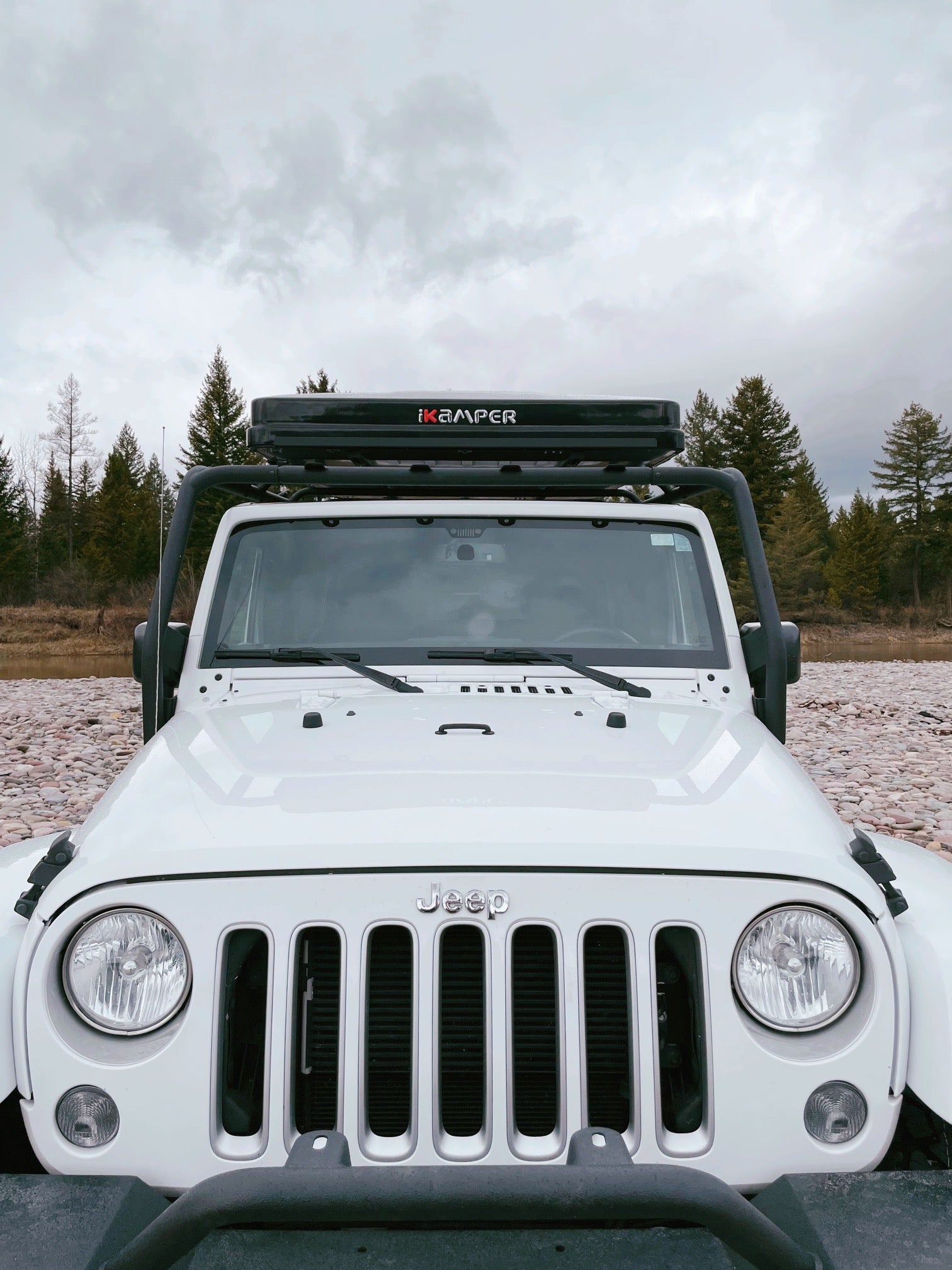 Front view of a white Jeep Wrangler with an iKamper rooftop tent, an ideal RV rental for off-grid nature adventures.