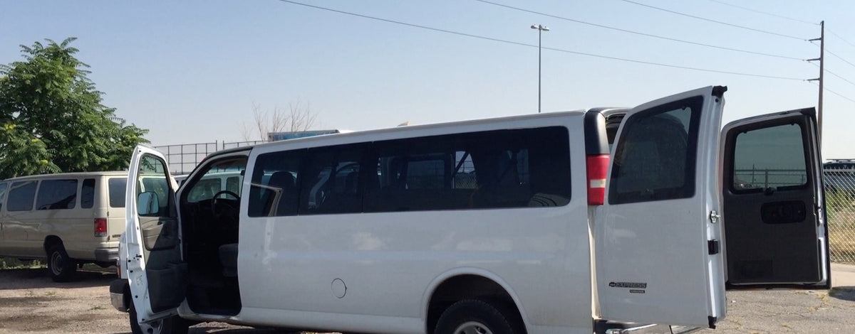Spacious white and beige passenger vans, some with open doors, ready for an RV rental adventure or group transport.