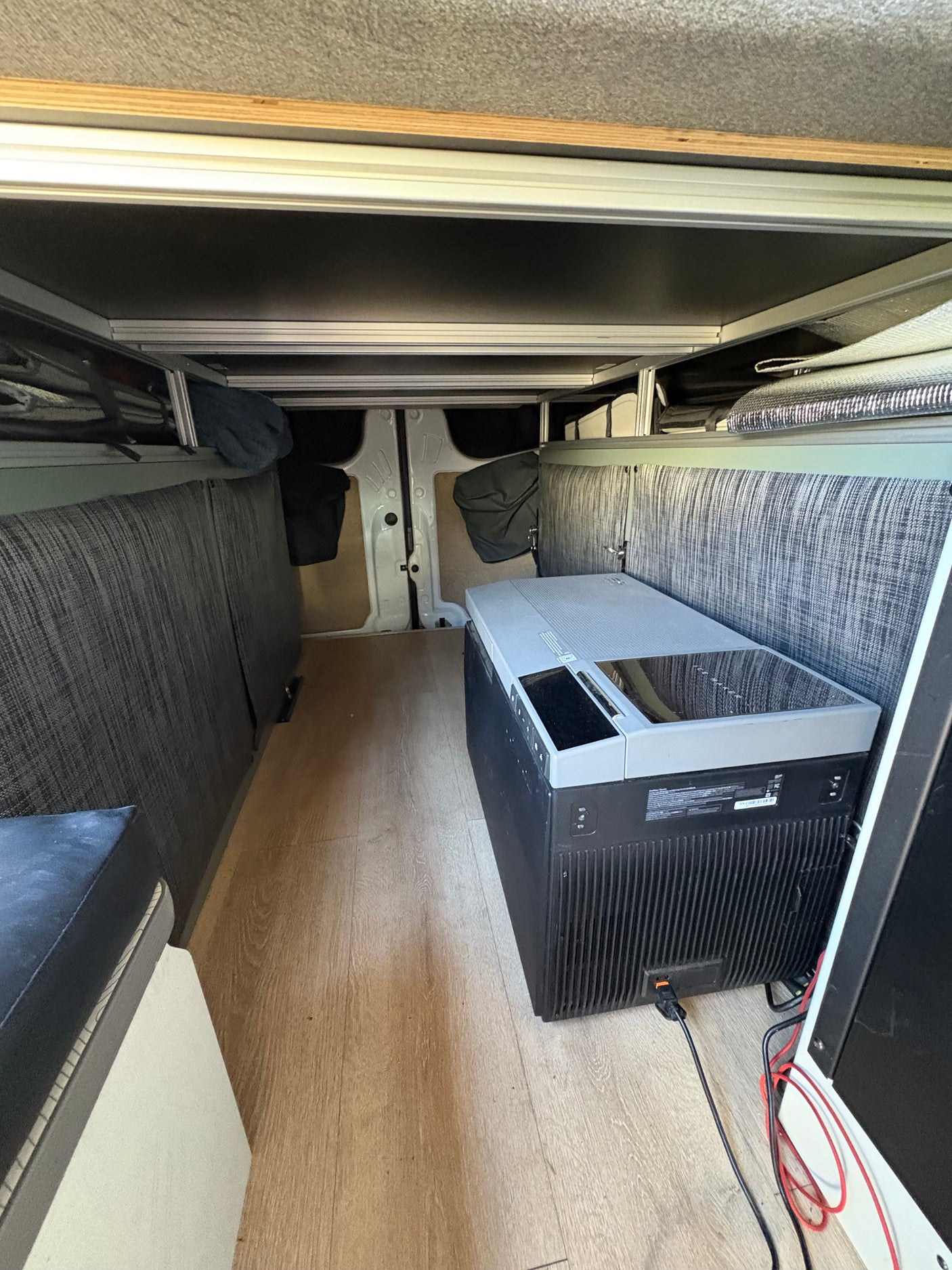 Inside an RV rental: a converted van interior with a portable fridge, bed platform, and organized storage.