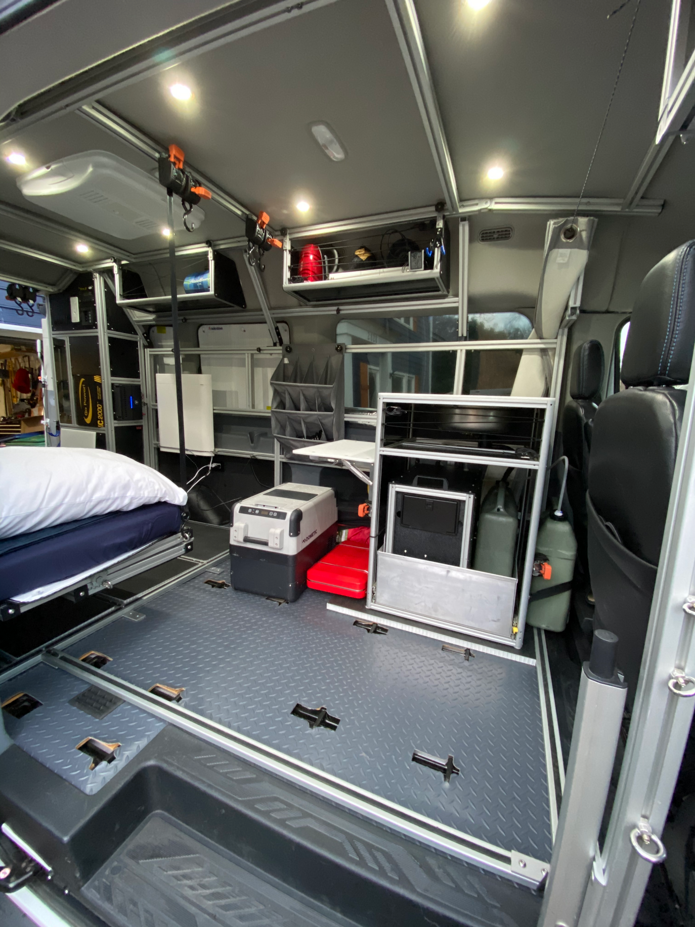 Modern rv rental interior: bed, Dometic cooler, ample modular storage, and diamond plate floor for adventure.