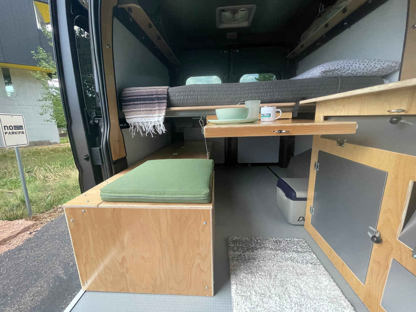 Inside this RV rental camper van: A versatile living space with cozy bed, bench seating, and a convenient pull-out table.