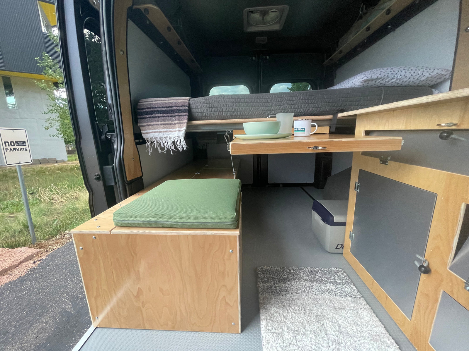 Inside this RV rental camper van: A versatile living space with cozy bed, bench seating, and a convenient pull-out table.