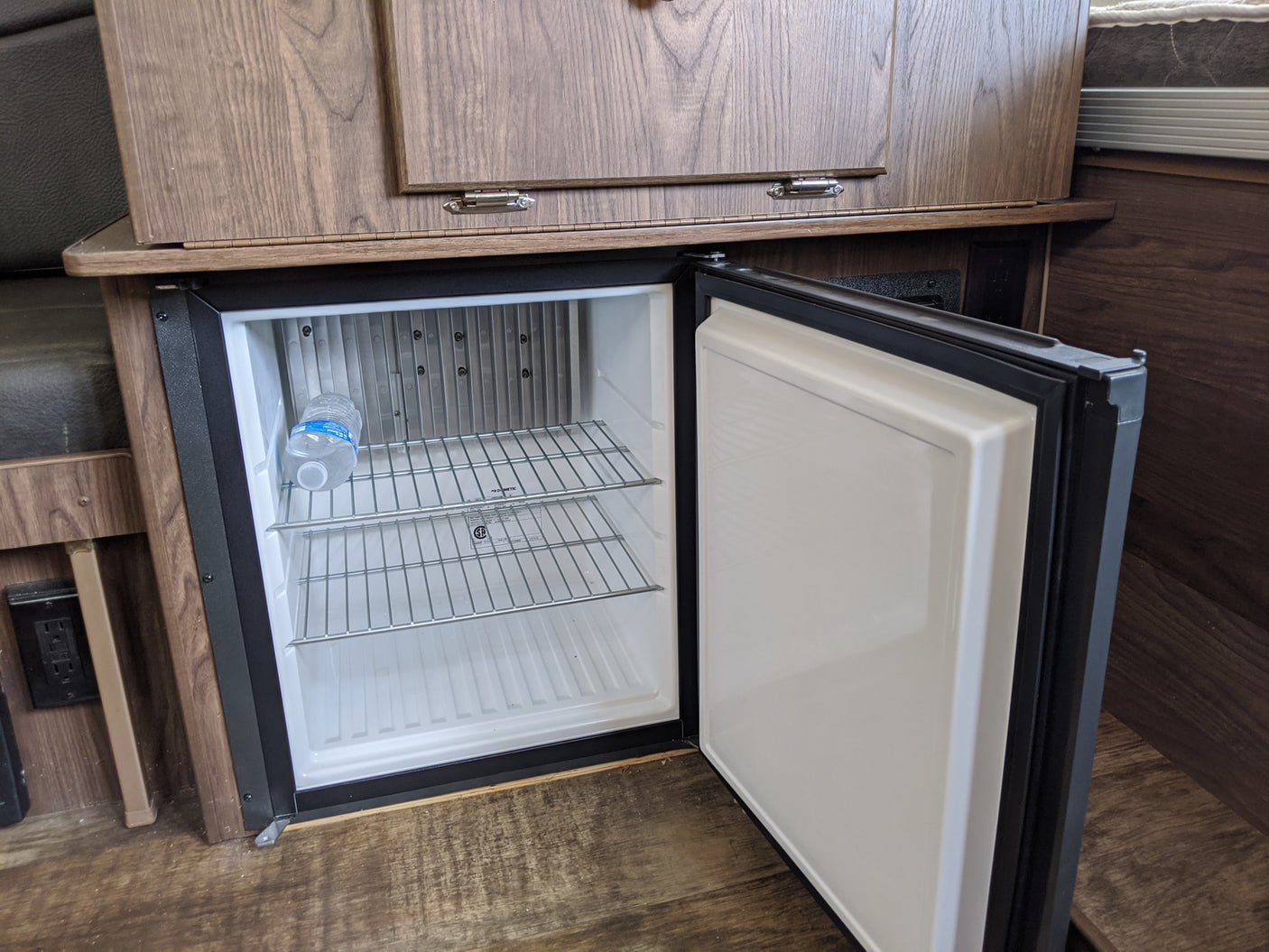 RV rental mini-fridge, open and clean with a water bottle, ideal for storing drinks and snacks on the road.