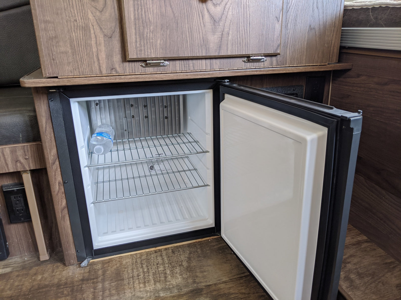 RV rental mini-fridge, open and clean with a water bottle, ideal for storing drinks and snacks on the road.