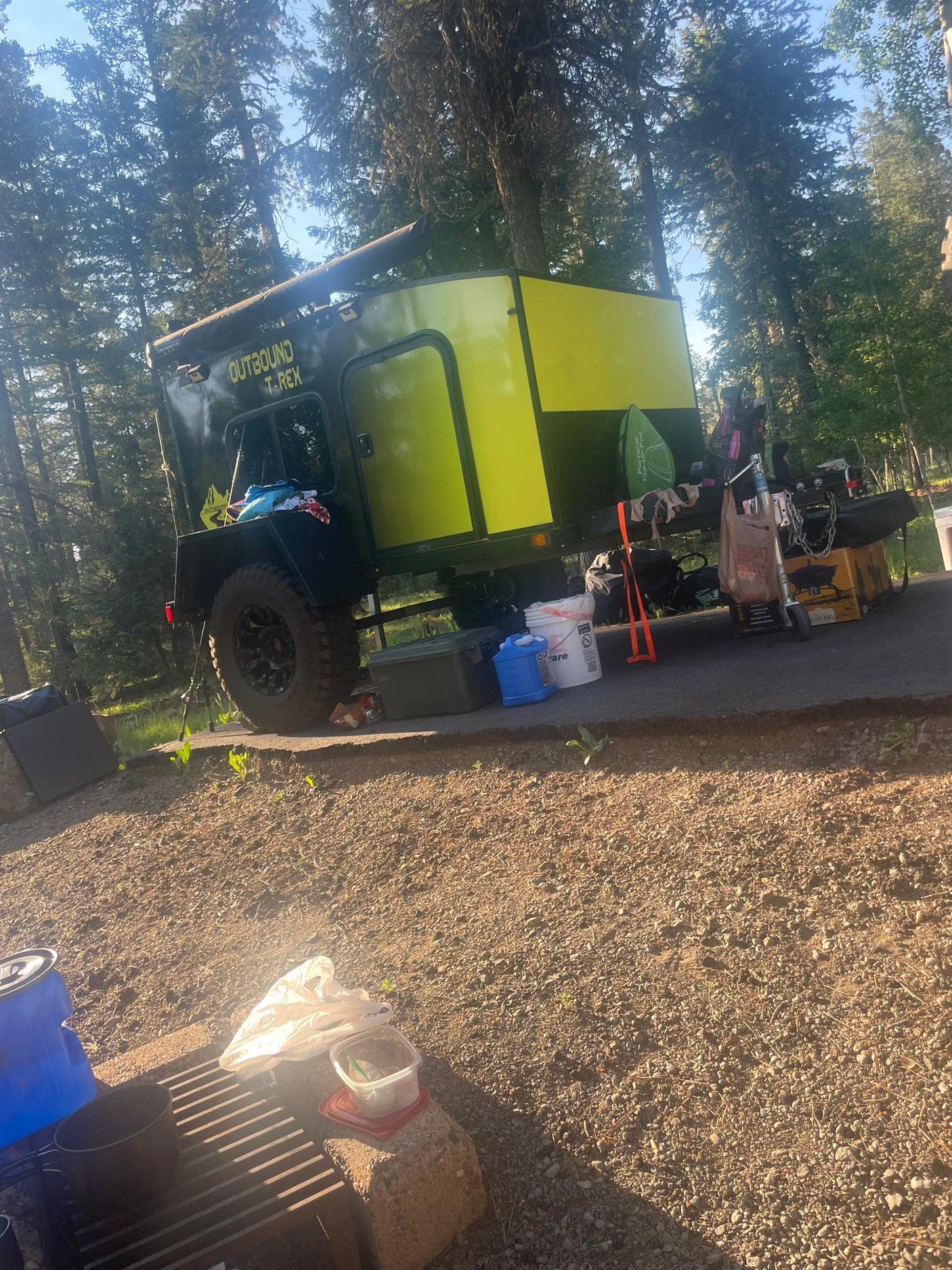This vibrant Outbound T-Rex off-road camper trailer, ready for adventure, offers an RV rental experience at a campsite.