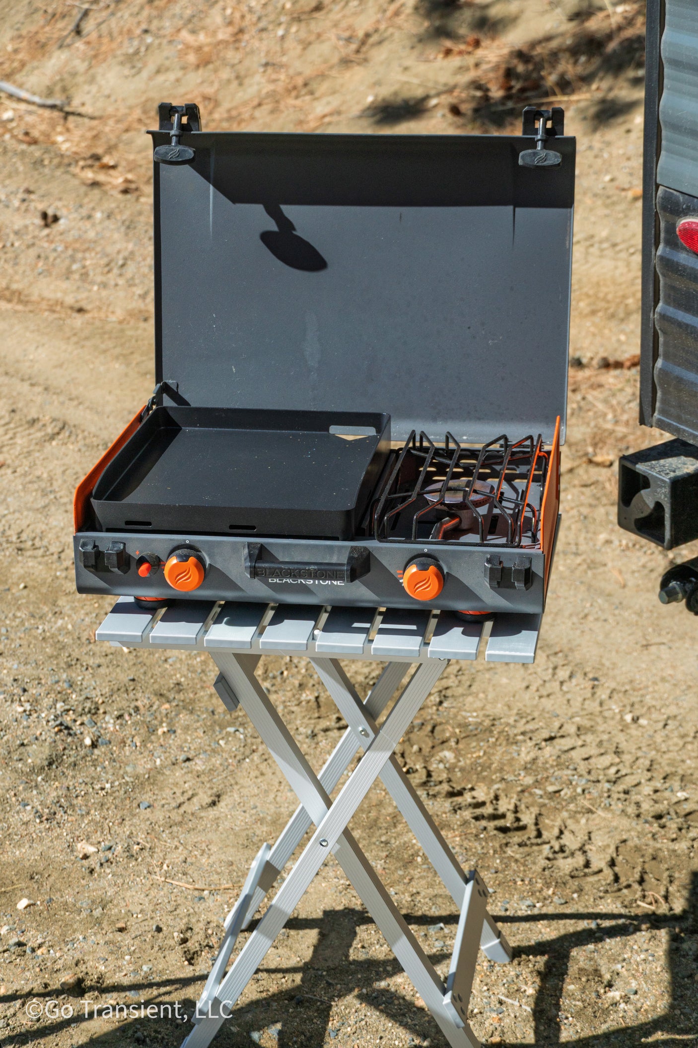 An RV rental must-have: A portable Blackstone griddle and stove on a folding table for outdoor campsite cooking.