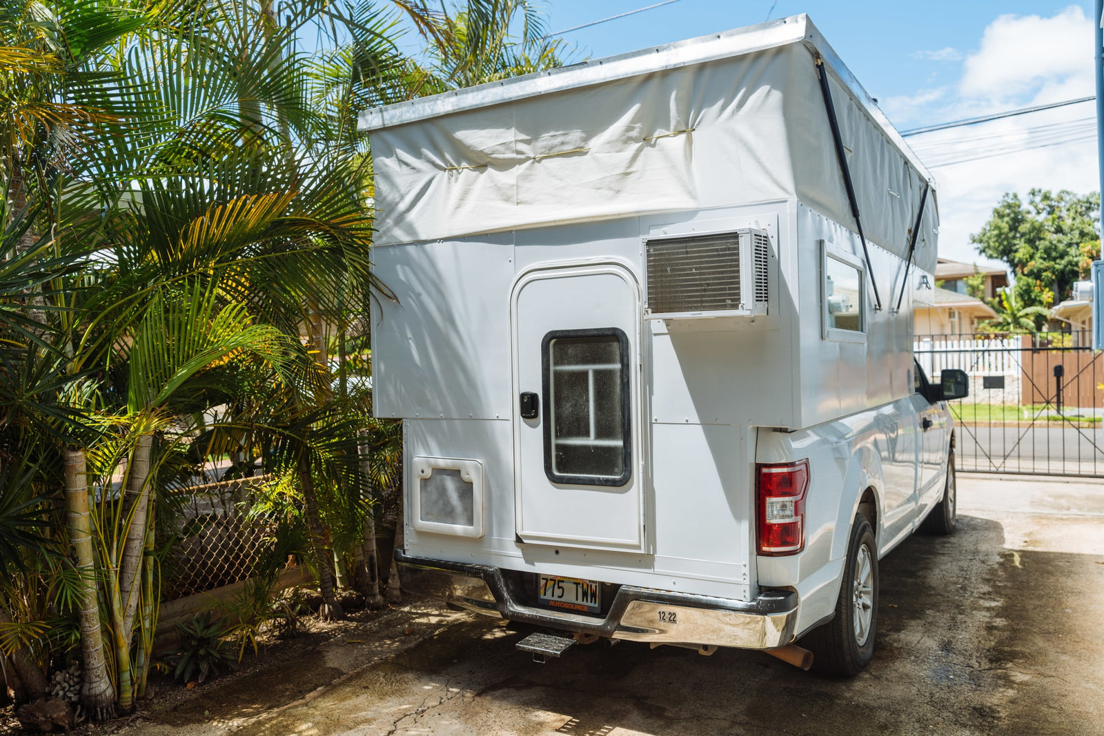 White truck with custom pop-top RV rental camper and AC unit