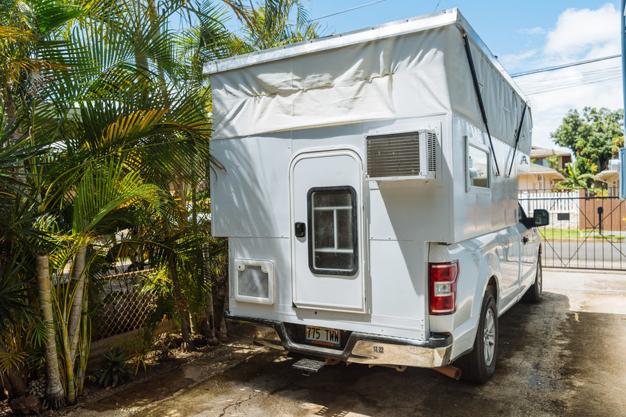 White truck with custom pop-top RV rental camper and AC unit