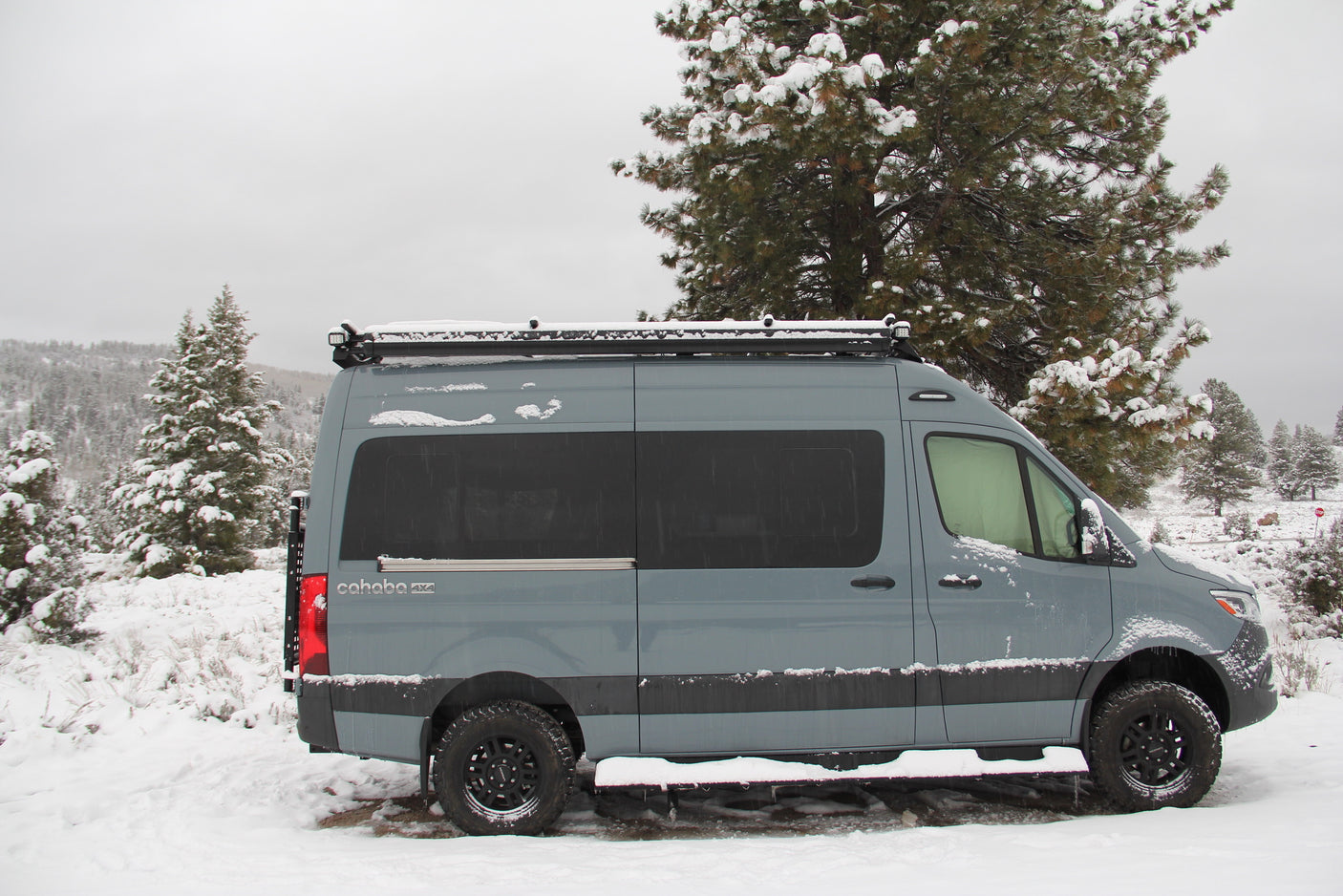 Grey 4x4 camper van parked in a snowy landscape, ready for your next winter rv rental adventure.