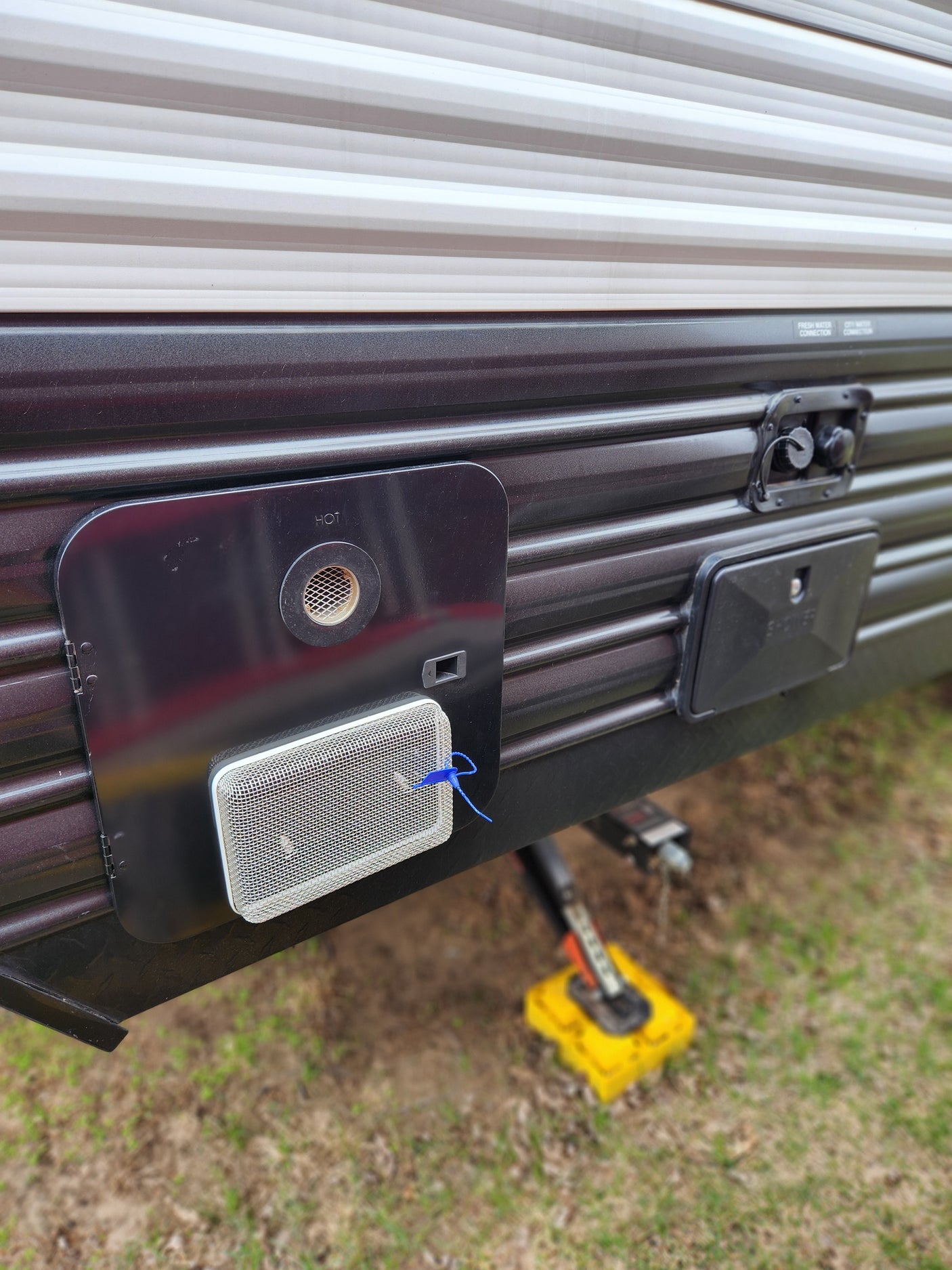 This RV rental's utility panel features a water heater access, outdoor shower, and fresh/city water connections on its side.