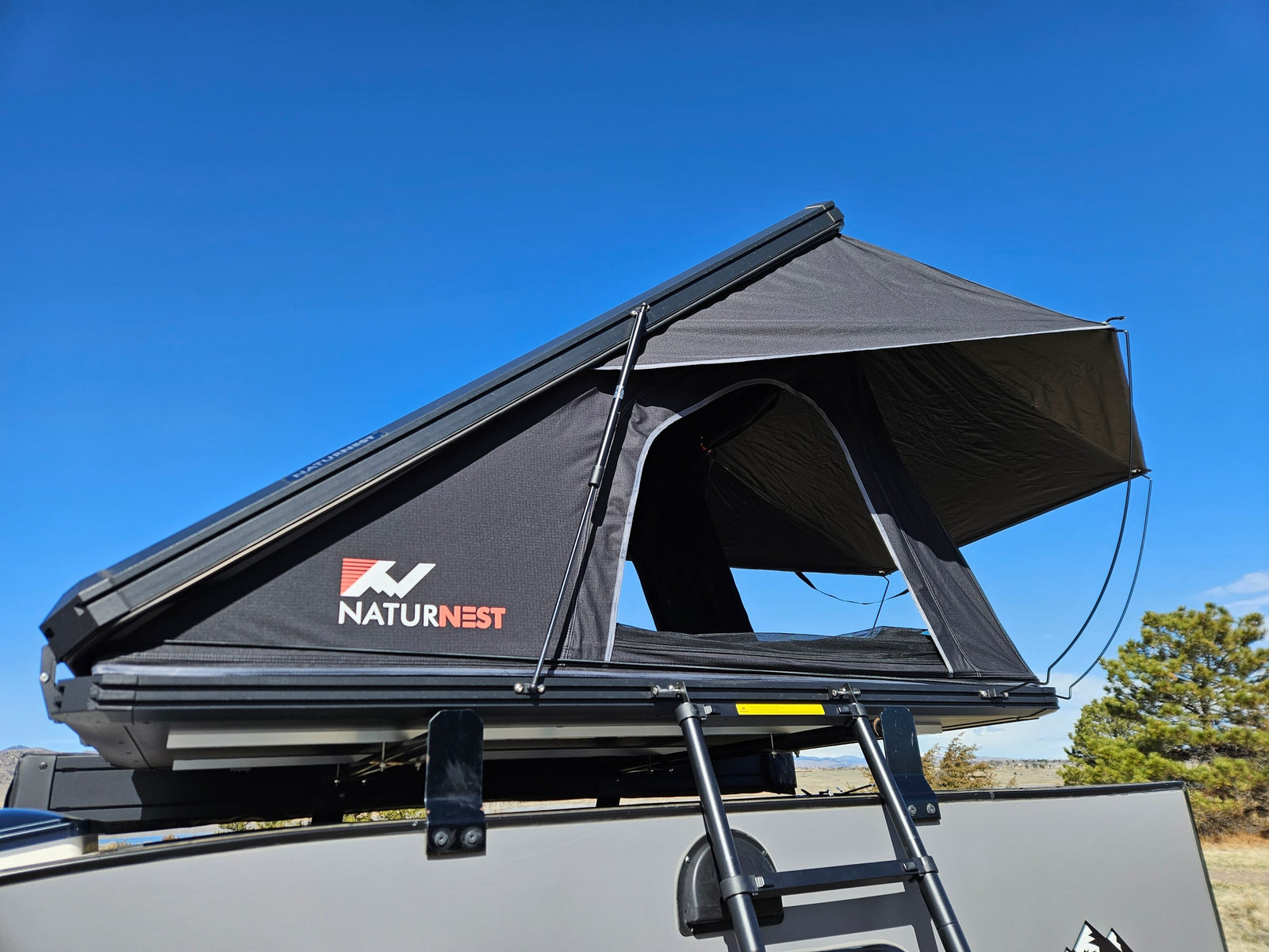 great for an RV rental trip.|Compact RV rental: A grey Escapade Camper with a black NatureNest rooftop tent deployed in a scenic Colorado landscape.|Black NaturNest rooftop tent deployed on an RV rental