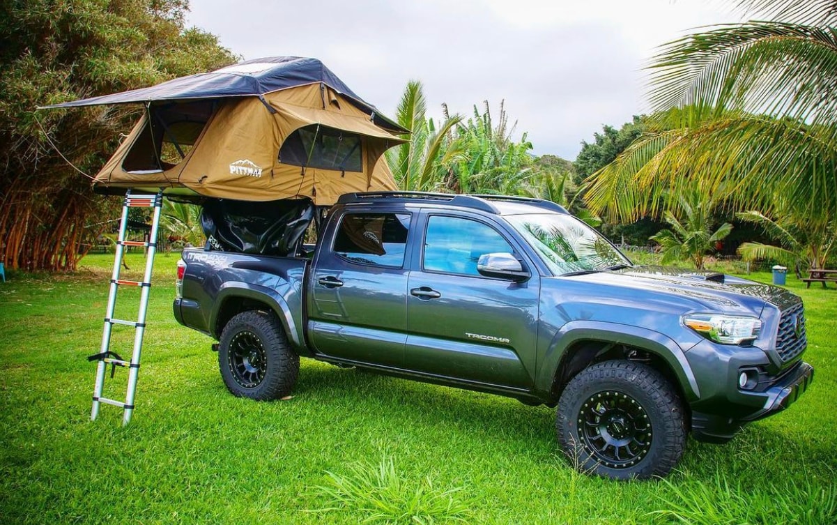 Gray pickup with a Pitmast rooftop tent & ladder on grass. A great RV rental alternative for camping & outdoor adventures. — photo 1