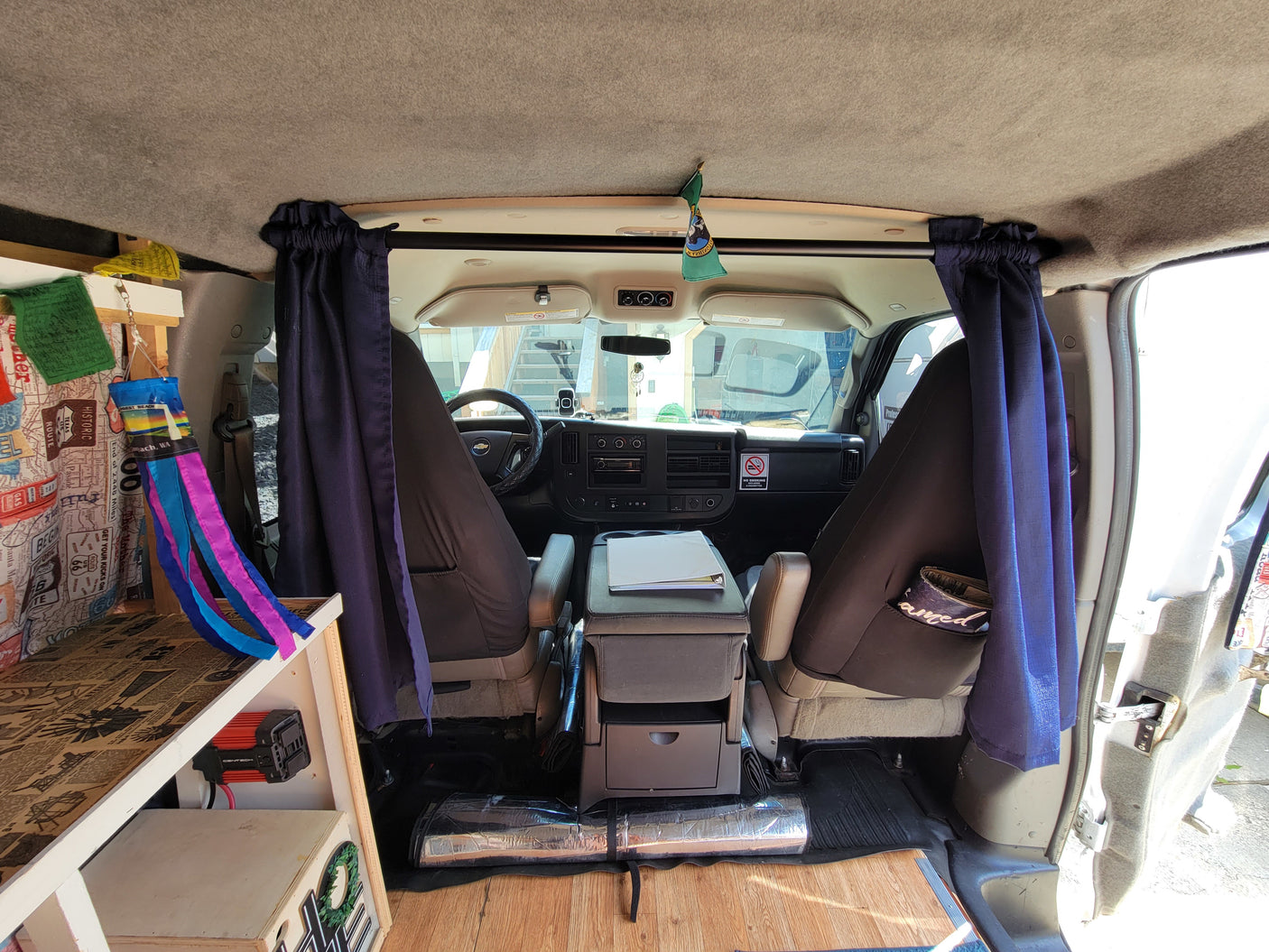 Cozy rv rental camper van interior. View from back showing custom built-ins, privacy curtains & dashboard.