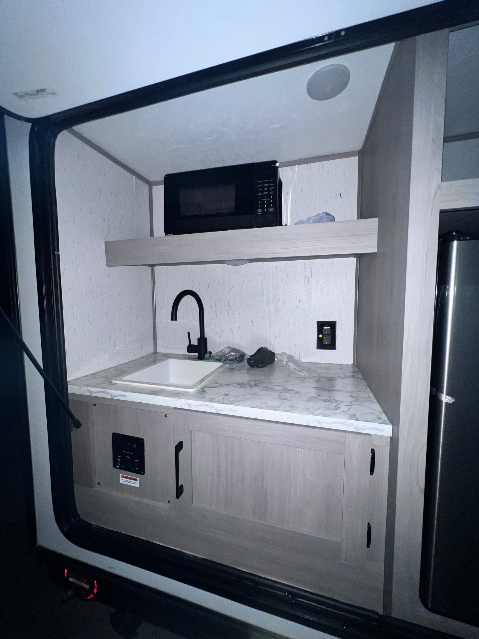 Inside an RV rental: a compact kitchen with sink, microwave, and refrigerator for convenience.