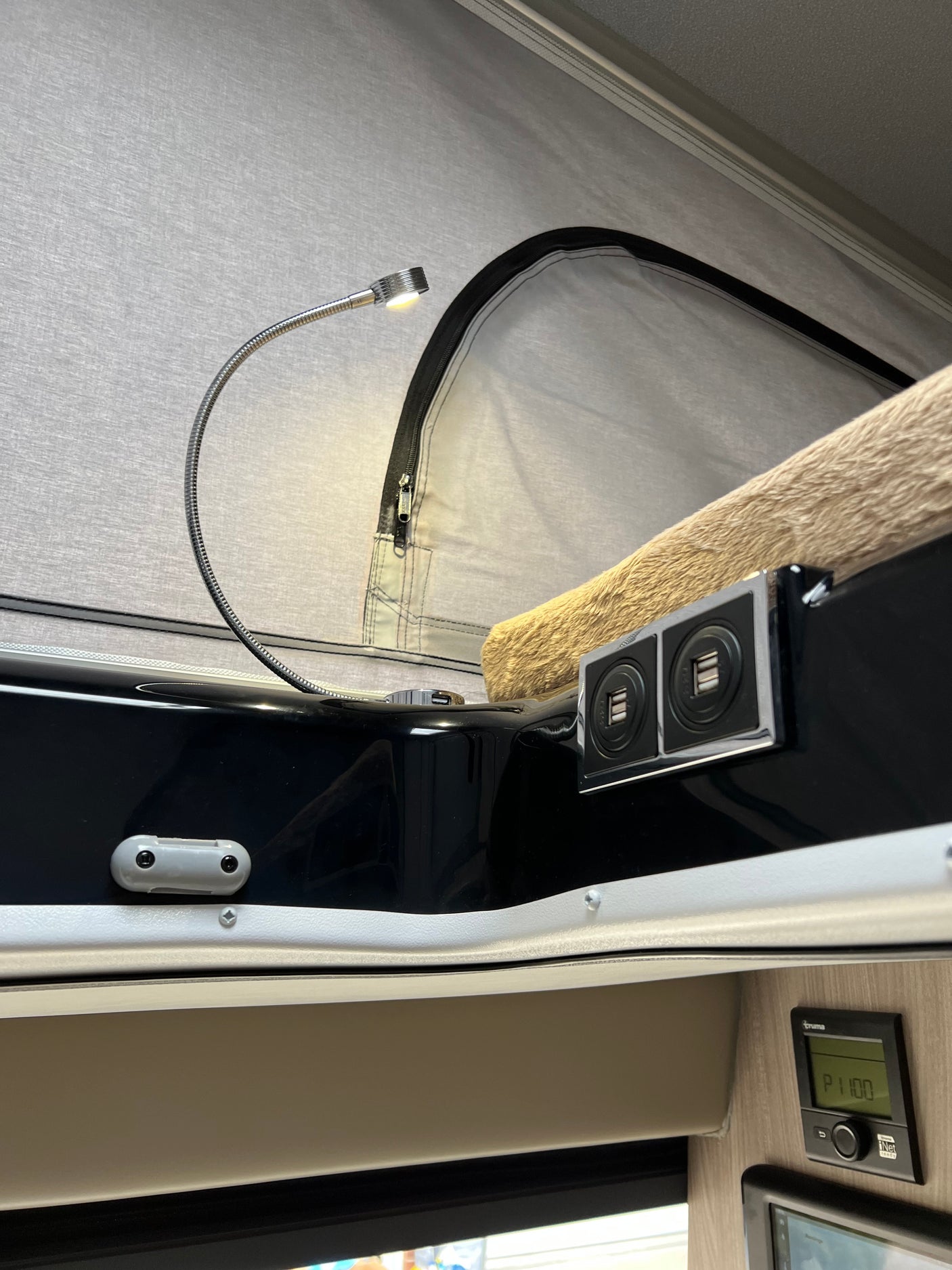 Cozy RV rental pop-top bed area with reading light, USB ports, and Truma control for comfort and convenience.