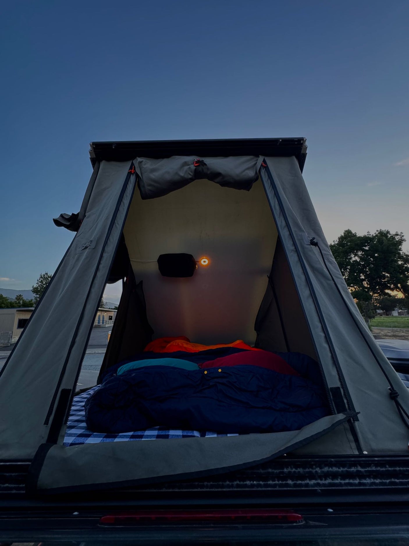 Cozy rooftop tent on a vehicle, perfect for your next RV rental camping trip. Bedding & warm light inside.