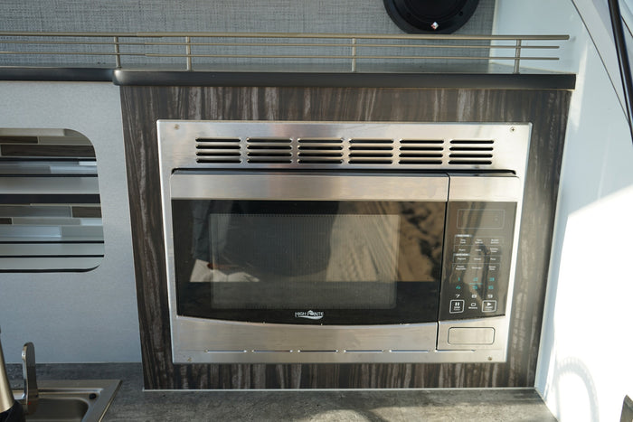 built-in stainless steel High Pointe microwave oven for convenient cooking.|A cozy RV rental interior with patterned cushions