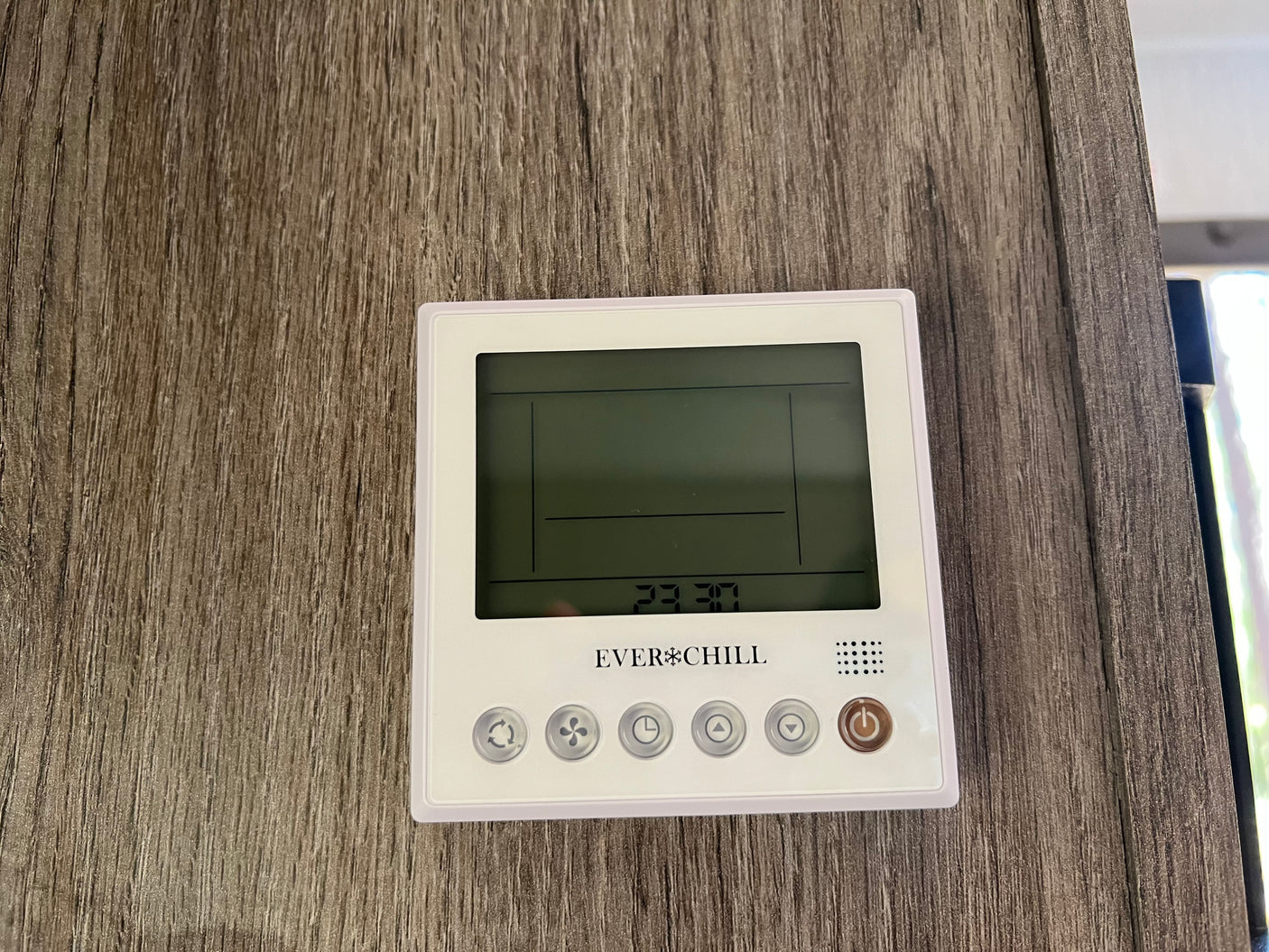 An EVERCHILL thermostat in an RV rental, with a digital display showing 23:30. Mounted on a wood-grain wall, with control buttons.