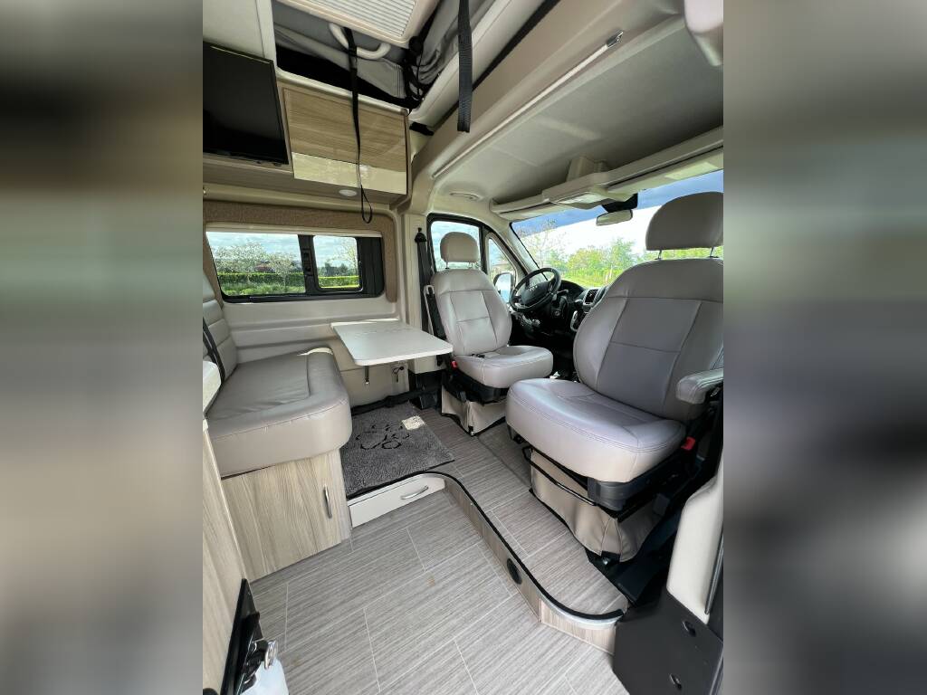 parked in a peaceful pine forest at sunset.|Spacious RV rental interior with swivel captain's chairs