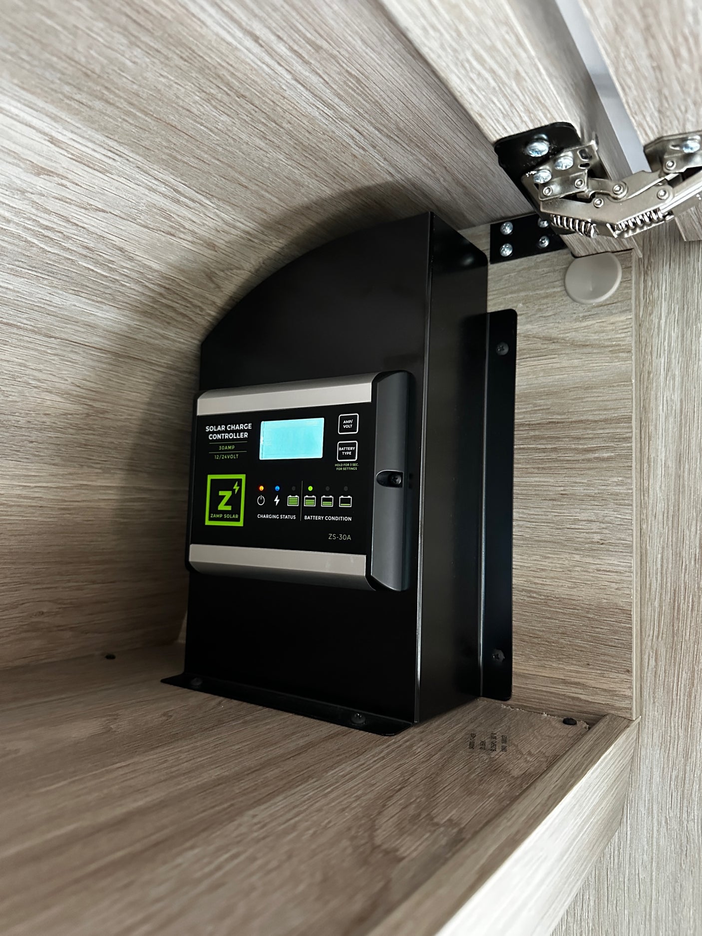 A Zamp Solar charge controller (ZS-30A) is mounted inside an RV rental cabinet, managing solar power for batteries.