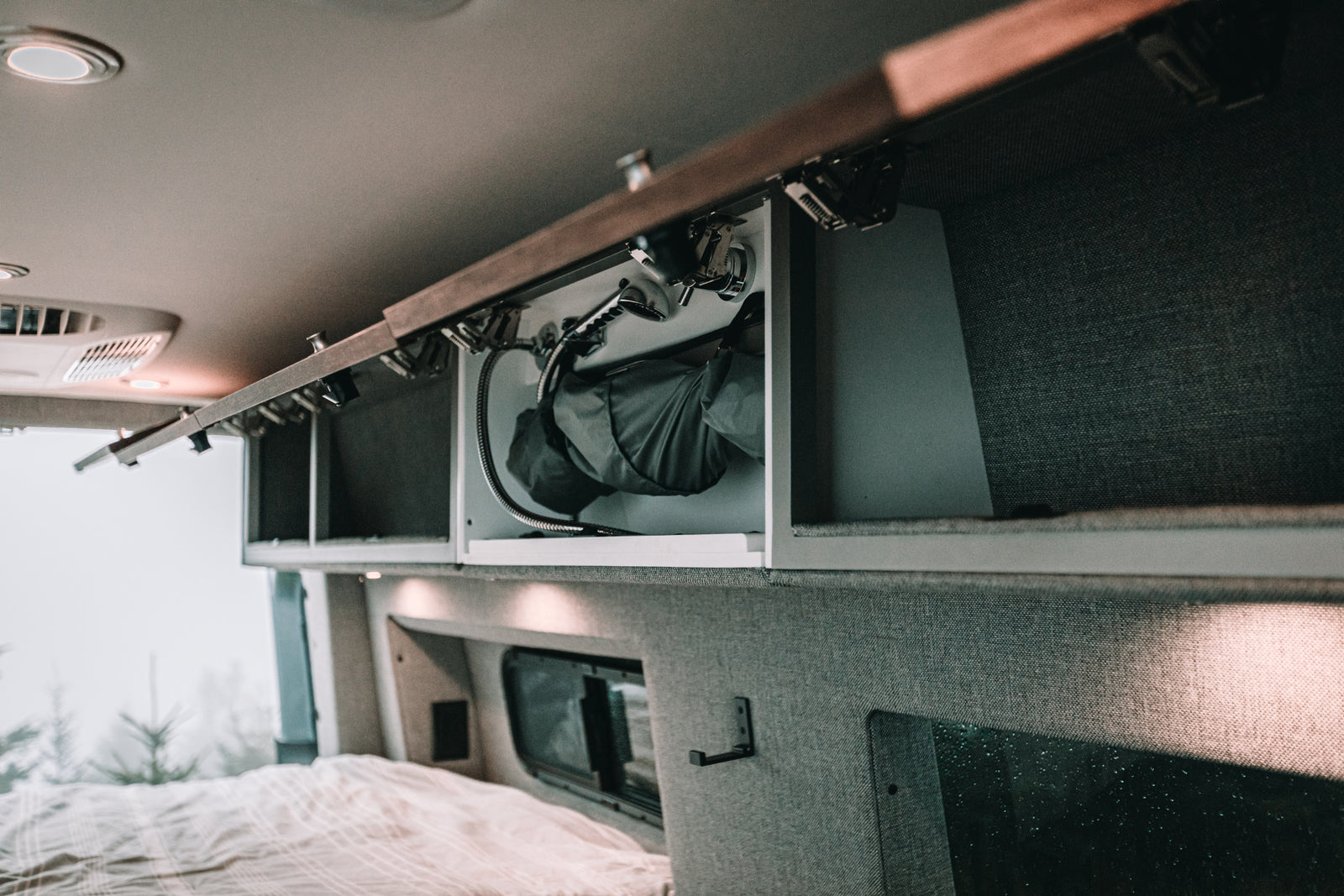 Explore this RV rental's smart campervan interior, featuring a pull-out shower, comfy bed, & scenic window view.