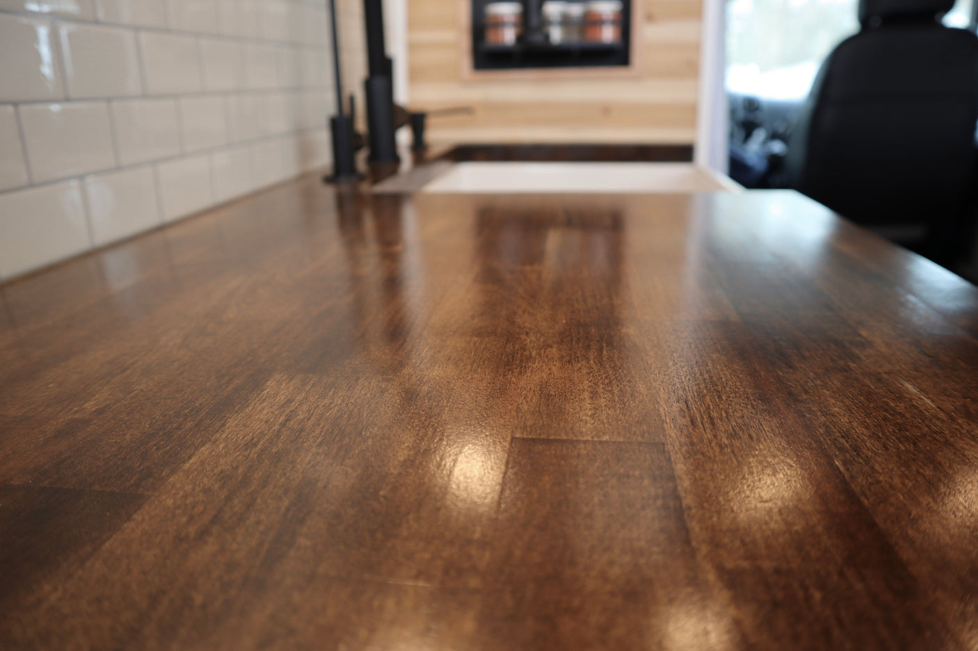 RV rental kitchen: A close-up of a rich wooden countertop, white subway tile, and modern black faucet in a sleek interior.