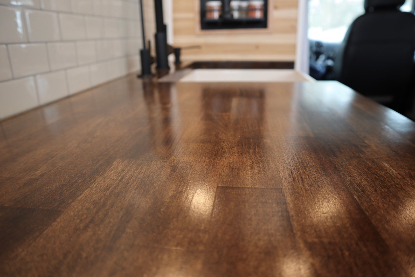 RV rental kitchen: A close-up of a rich wooden countertop, white subway tile, and modern black faucet in a sleek interior.