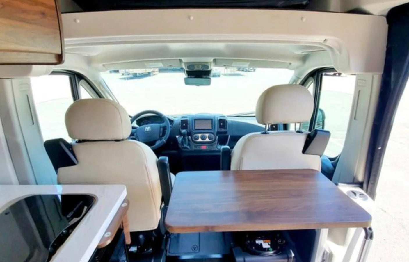 RV rental camper van: interior view of swiveling front seats, dining table, and kitchenette setup.