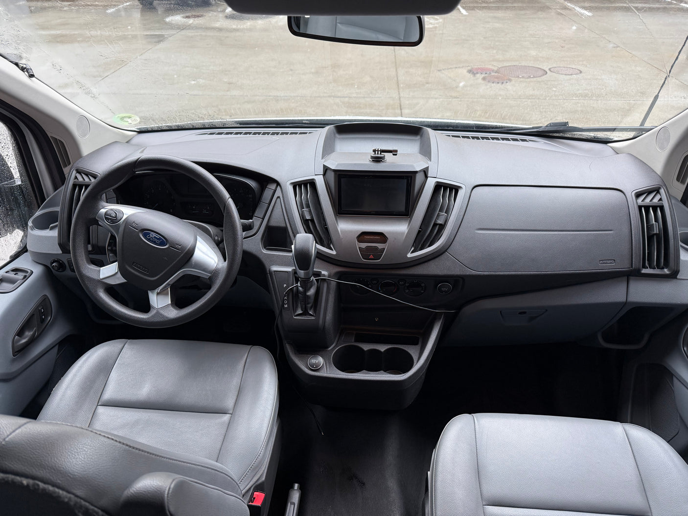 Interior of a grey Ford RV rental, detailing the driver's area with steering wheel, dashboard, and front seats.